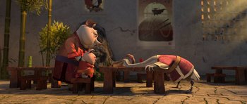 Movie still from “Kung Fu Panda 2” (2011), directed by Jennifer Yuh Nelson – A couple of pigs sitting on top of a wooden bench; Wide shot, High angle