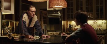 Movie still from “Labor Day” (2013), directed by Jason Reitman – Two people sitting at a table in a kitchen; Medium shot, Over the shoulder angle