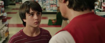 Movie still from “Labor Day” (2013), directed by Jason Reitman – A young boy talking to another young man in front of a counter; Close Up shot, Over the shoulder angle