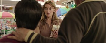 Movie still from “Labor Day” (2013), directed by Jason Reitman – A woman holding a book while standing next to other people; Close Up shot, Over the shoulder angle