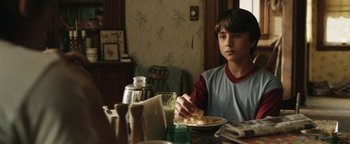 Movie still from “Labor Day” (2013), directed by Jason Reitman – A boy sitting at a table eating a bowl of food; Medium shot, Over the shoulder angle