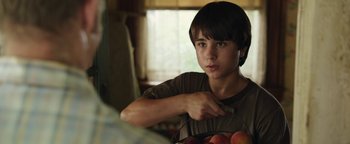 Movie still from “Labor Day” (2013), directed by Jason Reitman – A young boy holding a basket of apples; Close Up shot, Over the shoulder angle