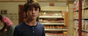 Movie still from “Labor Day” (2013), directed by Jason Reitman – A young boy standing in front of shelves of food; Close Up shot, Low angle