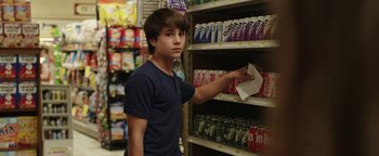 Movie still from “Labor Day” (2013), directed by Jason Reitman – A young man in a grocery store looking at soda cans; Medium shot, Low angle