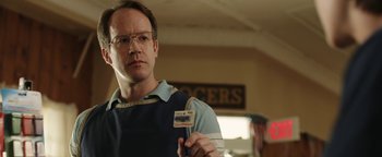 Movie still from “Labor Day” (2013), directed by Jason Reitman – A man holding up his id card in a room; Close Up shot, Over the shoulder angle
