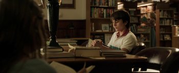 Movie still from “Labor Day” (2013), directed by Jason Reitman – A young boy sitting at a table with a stack of books; Medium shot, High angle