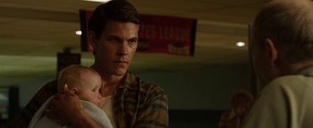Movie still from “Labor Day” (2013), directed by Jason Reitman – A man holding a baby in his arms while standing next to a wall; Close Up shot, Over the shoulder angle