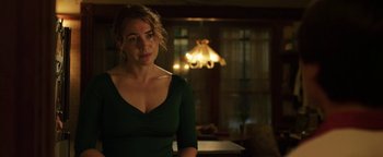 Movie still from “Labor Day” (2013), directed by Jason Reitman – A woman in a green dress standing in front of a lamp; Medium shot, Over the shoulder angle