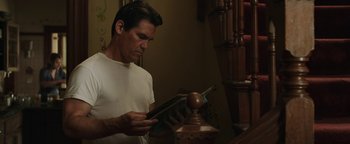 Movie still from “Labor Day” (2013), directed by Jason Reitman – A man looking at a book in his hands; Medium shot, Low angle