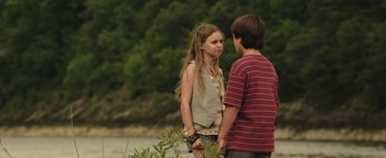 Movie still from “Labor Day” (2013), directed by Jason Reitman – A girl and a boy standing next to each other in front of trees; Medium shot, Over the shoulder angle