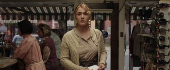Movie still from “Labor Day” (2013), directed by Jason Reitman – A woman standing in front of a store holding a receipt; Medium shot, Over the shoulder angle
