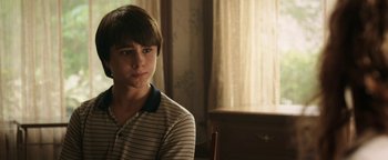 Movie still from “Labor Day” (2013), directed by Jason Reitman – A young man sitting in a chair in a room; Close Up shot, Over the shoulder angle