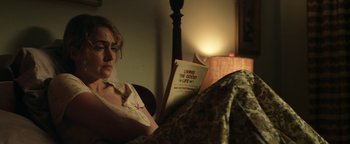 Movie still from “Labor Day” (2013), directed by Jason Reitman – A woman sitting in a chair reading a book; Medium shot, Low angle