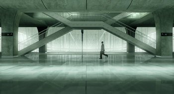 A man in a white shirt is walking in a building
