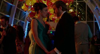 Movie still from “Laggies” (2014), directed by Lynn Shelton – A man and a woman holding hands in front of a wall of flowers; Medium shot, Low angle