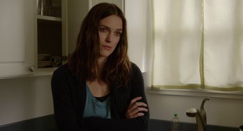 Movie still from “Laggies” (2014), directed by Lynn Shelton – A woman standing in front of a window with her arms crossed; Close Up shot, Over the shoulder angle