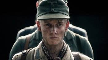 Movie still from “Land of Mine” (2015), directed by Martin Zandvliet – A man in a military uniform and a hat is standing in front of another man; Close Up shot, Over the shoulder angle