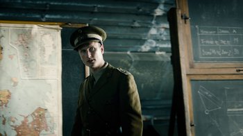 Movie still from “Land of Mine” (2015), directed by Martin Zandvliet – A man in a military uniform standing in a room; Medium shot, Low angle