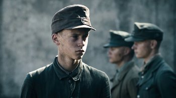 Movie still from “Land of Mine” (2015), directed by Martin Zandvliet – A young man in a military uniform is looking to his left; Close Up shot, Over the shoulder angle