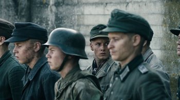 Movie still from “Land of Mine” (2015), directed by Martin Zandvliet – A group of men standing next to each other wearing uniforms; Medium shot, Over the shoulder angle
