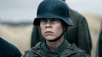 Movie still from “Land of Mine” (2015), directed by Martin Zandvliet – A man wearing a military helmet and a uniform; Close Up shot, Over the shoulder angle