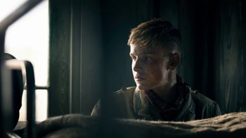 Movie still from “Land of Mine” (2015), directed by Martin Zandvliet – A young man looking into the distance in a dark room; Close Up shot, Over the shoulder angle