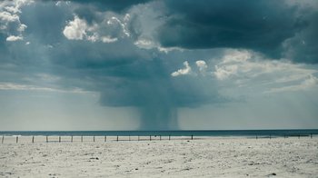 Movie still from “Land of Mine” (2015), directed by Martin Zandvliet – A storm is coming in the distance over the ocean; Extreme Wide shot, Low angle