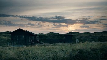 Movie still from “Land of Mine” (2015), directed by Martin Zandvliet – A couple of houses sitting in the grass; Extreme Wide shot, Low angle