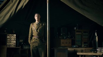 Movie still from “Land of Mine” (2015), directed by Martin Zandvliet – A man in a military uniform standing in front of a tent; Medium shot, Low angle