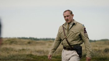 Movie still from “Land of Mine” (2015), directed by Martin Zandvliet – A man in a field wearing a uniform and holding a rifle; Medium shot, Low angle