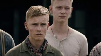 Movie still from “Land of Mine” (2015), directed by Martin Zandvliet – Two young men standing next to each other in front of a building; Close Up shot, Low angle