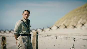 Movie still from “Land of Mine” (2015), directed by Martin Zandvliet – A man standing next to a barbed wire fence; Medium shot, Low angle