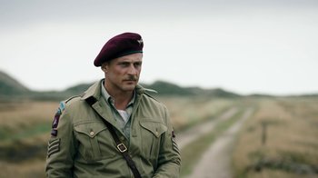 Movie still from “Land of Mine” (2015), directed by Martin Zandvliet – A man in a military uniform standing on a dirt road; Medium shot, Low angle