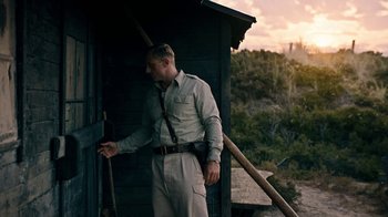 Movie still from “Land of Mine” (2015), directed by Martin Zandvliet – A man standing in front of a wooden building; Medium shot, Low angle