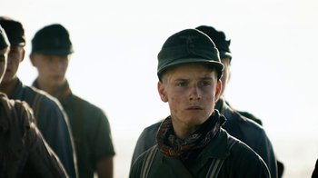 Movie still from “Land of Mine” (2015), directed by Martin Zandvliet – A young man wearing a hat and a bandana; Close Up shot, Low angle