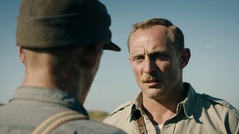 Movie still from “Land of Mine” (2015), directed by Martin Zandvliet – A man with a beard and mustache talking to another man; Close Up shot, Over the shoulder angle