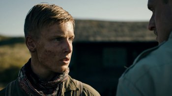 Movie still from “Land of Mine” (2015), directed by Martin Zandvliet – A man with a bandana on his face looking to his left; Close Up shot, Over the shoulder angle