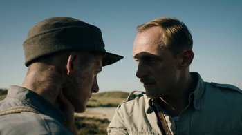 Movie still from “Land of Mine” (2015), directed by Martin Zandvliet – Two men standing next to each other on a dirt field; Close Up shot, Over the shoulder angle