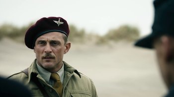 Movie still from “Land of Mine” (2015), directed by Martin Zandvliet – A man in a military uniform wearing a hat and tie; Close Up shot, Over the shoulder angle