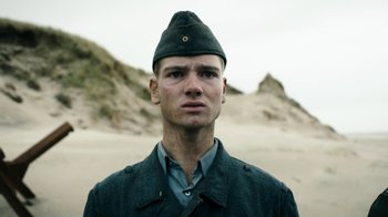 Movie still from “Land of Mine” (2015), directed by Martin Zandvliet – A man in a military uniform standing in front of a sand dune; Close Up shot, Low angle