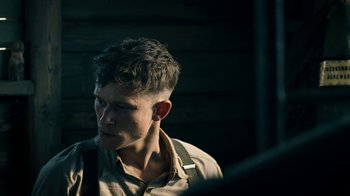 Movie still from “Land of Mine” (2015), directed by Martin Zandvliet – A young man with short hair is looking to his left; Close Up shot, Over the shoulder angle