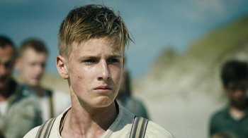 Movie still from “Land of Mine” (2015), directed by Martin Zandvliet – A young man with a serious look on his face; Close Up shot, Low angle