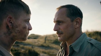 Movie still from “Land of Mine” (2015), directed by Martin Zandvliet – A man and a boy face to face in a field; Close Up shot, Over the shoulder angle