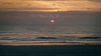 Movie still from “Land of Mine” (2015), directed by Martin Zandvliet – The sun is setting over the ocean on a cloudy day; Extreme Wide shot, Low angle