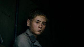 Movie still from “Land of Mine” (2015), directed by Martin Zandvliet – A young man in a gray shirt is looking at the camera; Close Up shot, Low angle