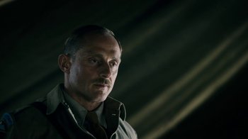 Movie still from “Land of Mine” (2015), directed by Martin Zandvliet – A person wearing a jacket and a tie; Close Up shot, Low angle