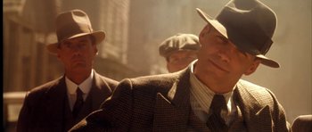 Movie still from “Last Man Standing” (1996), directed by Walter Hill – A man in a suit and a hat is standing next to another man in a suit; Close Up shot, Over the shoulder angle