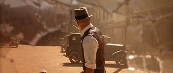 Movie still from “Last Man Standing” (1996), directed by Walter Hill – A man wearing a hat walking down a street; Medium shot, Over the shoulder angle