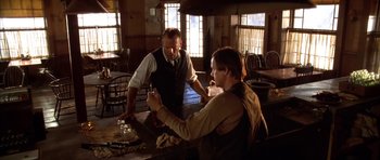 Movie still from “Last Man Standing” (1996), directed by Walter Hill – Two men are standing at a table and one is cutting a cake; Medium shot, Low angle