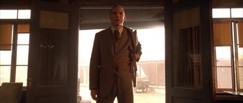 Movie still from “Last Man Standing” (1996), directed by Walter Hill – A man in a suit and tie standing in front of a window; Medium shot, Low angle